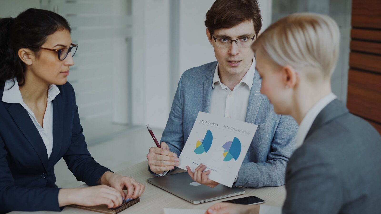 Two individuals seated at a table reviewing a document with charts during a discussion.